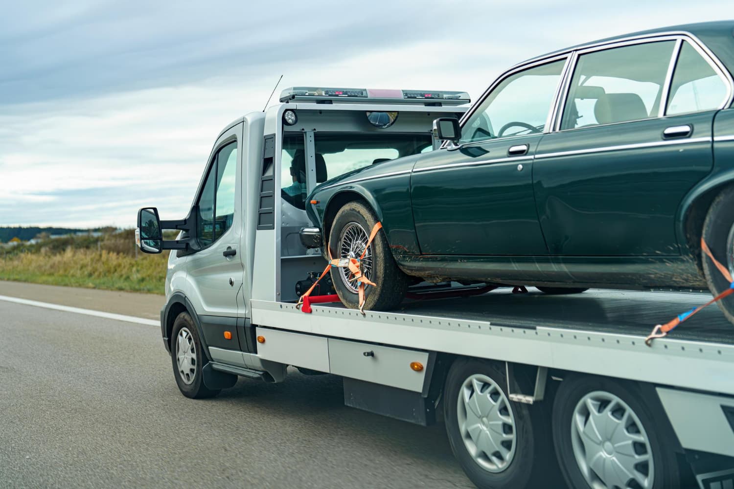 Classic sedan loaded and strapped down on a flatbed tow truck